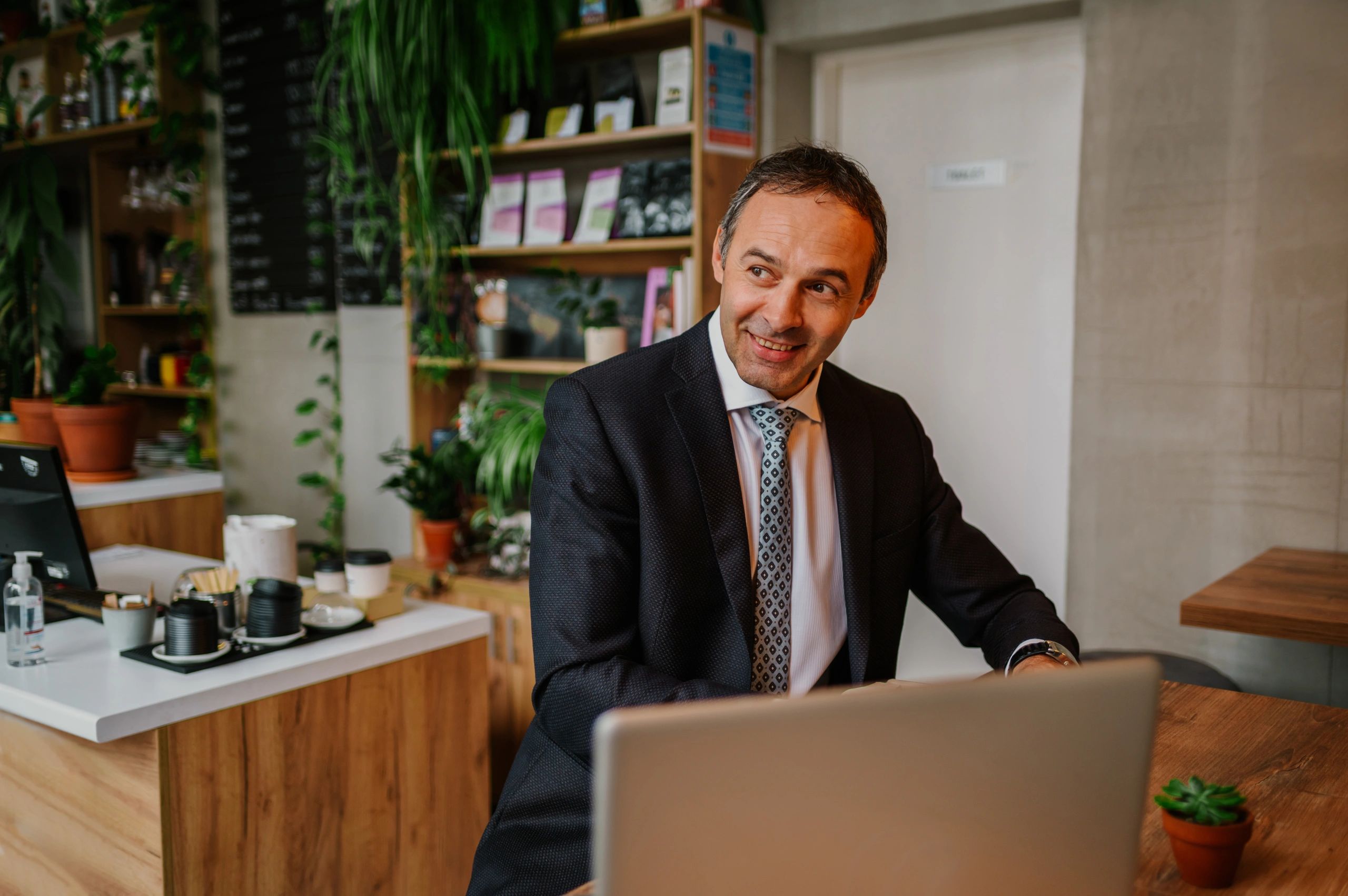 Smiling man in an elegant suit looking into the distance while in a coffee shop